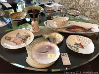 Full set displayed on round table with various plates, serving pieces, decorative plate and bell visible