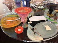 Overview of decorative glassware and trays including Michael Aram trays, Kosta Boda pieces, and assorted art glass vases