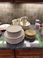 Full view of all textured dishware including stacked plates, bowls, mugs, and pottery pieces