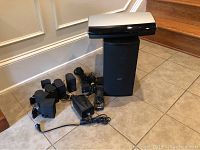 Overview of entire lot on tile floor including media center, PS48 speaker, surround satellites, power supply, remote and cables