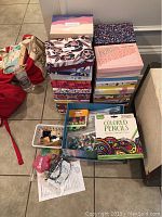 Four stacks of colorful Birchbox craft boxes, a box of colored pencils, assorted beads, yarn, and various small crafting supplies on floor.