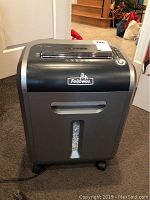 Front view of the Fellowes paper shredder showing the brand logo, paper slot on top, and pull-out bin with viewing window for shredded contents.