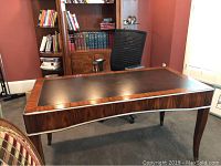 Front view of full executive desk showing curved front, wood grain and leather top