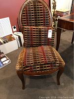 Front view of the silk/wool upholstered oval back chair with a patterned pillow and extra fabric on the seat.