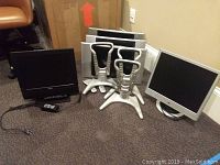 Three Sharp Aquos 15-inch monitors with stands and two remotes, one Memorex 15-inch monitor, one HP 17-inch monitor arranged on floor.