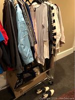 Rack of various women's jackets, sweaters, hoodies, blouses, and scarves hung on hangers. Several layers of clothing visible including a blue jacket and a patterned sweater.
