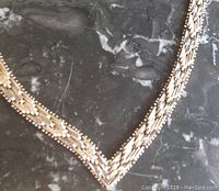 Close-up photo of one silver necklace showing linked design and V-shaped center.