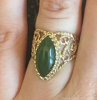 Ring worn on finger showing jade stone and filigree design