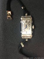 Overall front view of the rectangular silver-tone GRUEN wristwatch with black fabric band showing the dial and number markers clearly.