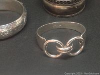 Photo showing three silver bangles including one with chain link detail and two with engraved and embossed designs.
