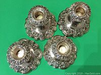 Set of four silver plated candle sticks viewed from top showing removable drip tops and detailed embossed floral patterns.