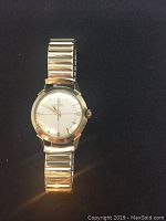 Front view of Omega Automatic wristwatch showing gold-tone case, silver crosshair dial with gold-tone indices and baton hands