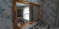 Full view of gilt wood framed wall mirror reflecting room interior