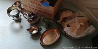 Silverplate chafing and serving dishes with some wrapped in cloth, arranged on floor.