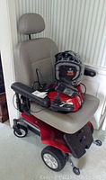 Front view of GoChair motorized wheelchair showing seat, base, joystick, charger and helmet on seat