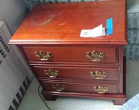 Front view of Pennsylvania House hardwood end table showing three drawers with brass pulls and wear on the wooden surface.