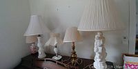 Six table lamps on a furniture piece, showing various styles and materials.