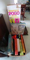 Photo showing boxed Maverick Pogo Stick and stacked vintage board games including Risk, The Game of 99 and others