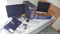 Dell desktop computer tower, Dell monitor, Lenovo laptop, Insignia monitor, and accessories on mattress.