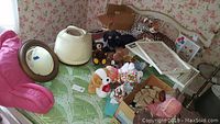 Overview of lot showing plush toys, breakfast tray, reading pillow, hair dryer, and mirror on a green quilted surface and pink chair nearby.