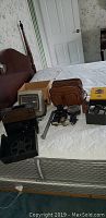 Overview of lot showing projector, lenses, lamps, carry bag, and viewer on mattress.