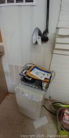Zenith dehumidifier with assorted alarm clocks on a black wire rack on top, positioned near a wall.