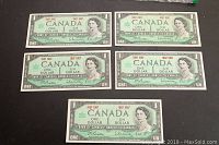 Five uncirculated Canadian 1 dollar bills front side showing Queen Elizabeth II portrait and 1867-1967 dates.