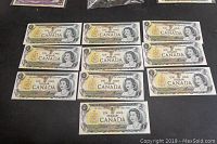 Ten Canadian one dollar bills laid out face up showing Queen Elizabeth II portrait.