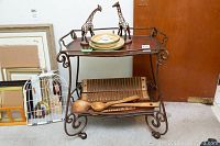 Full view of metal frame tea cart holding various items including wooden spoons, antique cigar roller, and decorative giraffe figures on top shelf (not included).