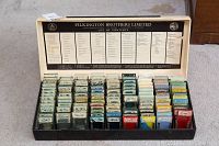 Open wooden box showing multiple rows of glass slides organized inside, labeled compartments under lid