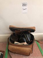 Top view of open vintage leather camera case showing camera and lens cases inside.