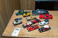 Overview of all ten diecast model vehicles arranged on wood table, showing variety of vintage trucks and classic cars.