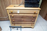 Front view of wood dresser showing three drawers with wooden knobs, labels on the middle drawer, and stereo equipment on top (not included).