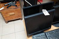 Two black computer monitors side by side on a table with keyboards in front, one Sharp and one Acer, both flat screen monitors.