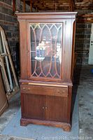 Full view of the wood display cabinet with glass door and storage below.
