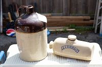 Photo of stoneware jug and bed warmer side by side on a plastic table outdoors.