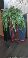 Full view of the wooden plant stand holding the silk fern, showing height and overall condition.