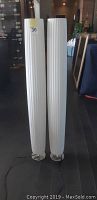 Pair of 48-inch white fabric floor lamps standing upright on dark wood floor with round metal bases visible.