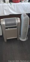 View of the Lasco heater and Honeywell oscillating tower fan side by side on floor.