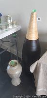 Tall bamboo and black vase with textured wrap next to smaller ceramic and glass vases