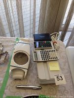 Top-down photo showing electric sealer, dicer, two calculators, and small flashlight on table near window.