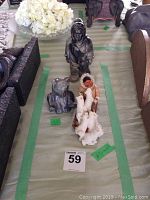 Photo showing all three items arranged in a row: standing stone carving figure, bear stone carving, and sled dog figurine.