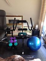 Front view of exercise chair with weights on rack and blue exercise ball nearby