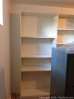 Single white shelving unit with three shelves and adjustable peg holes visible on the inside sides, showing wear and marks.