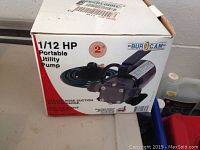 Photo of the product box showing brand Burcam, 1/12 HP portable utility pump, indicating garden hose suction and discharge capability with non-corrosive pump body.