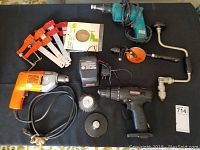 Full lot on black table showing drills, clamps, hand drills, wire brush attachments and sanding disc.