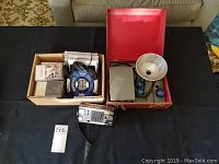 Overview of entire lot on black surface including boxes, camera with case, flash unit, radio, Walkman with headphones, cassette tapes, and CDs
