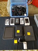 Overall view of lot on table including iPhones, iPad, boxes, smartwatch and cables