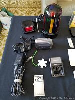 View of Canon ZR500 camcorder, power adapters, rechargeable batteries, battery charger, green USB cable, and remote control on table.