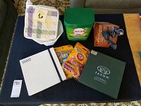 Full spread of lot contents on table showing placemats, knives, block, cleaning supplies, linens and fruit bowl